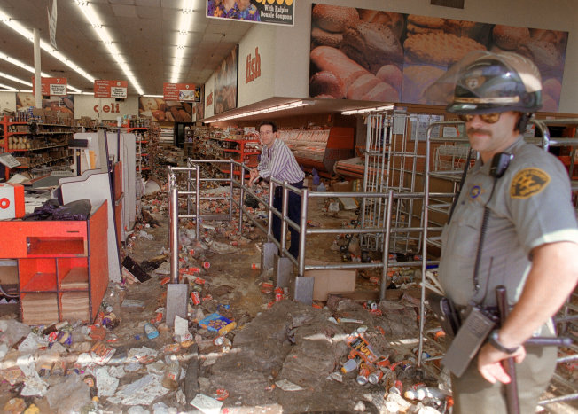 A store owner and a Los Angeles Police Department officer look at the damage caused by looters on April 1992, in Los Angeles.